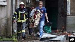 A man carries belongings out from an apartment building damaged by a Russian attack in Sumy, Ukraine, July 3, 2023.
