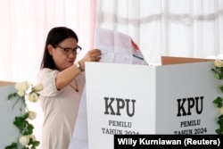 Seorang perempuan sedang mencoblos di sebuah TPS di Solo, Jawa Tengah, Rabu, 14 Februari 2024. (Foto: Willy Kurniawan/Reuters)
