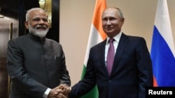 Presiden Rusia Vladimir Putin berjabat tangan dengan Perdana Menteri India Narendra Modi sebelum pertemuan mereka di sela-sela KTT Organisasi Kerja Sama Shanghai (SCO) di Bishkek, Kyrgyzstan, 13 Juni 2019. (Sputnik/Grigory Sysoyev/Kremlin via REUTERS)