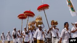 Anggota komunitas Hindu kembali dari upacara di pantai di distrik Kerobokan, Bali, 3 Januari 2024. (David GANNON / AFP)
