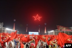 지난해 4월 평양 김일성 광장에서 열린 북한 조선인민혁명군 창건 90주년 열병식에서 주민들이 붉은 깃발을 흔들고 있다.