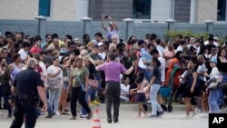 FILE - People gather across the street from a shopping center after a shooting May 6, 2023, in Allen, Texas.