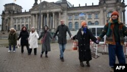 Demonstrators hold hands to form a human chain around the Reichstag building in Berlin, Germany, Feb. 3, 2024, during a rally to protest right-wing politics.