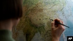 An artist paints a globe at a studio in London, Feb. 27, 2024.