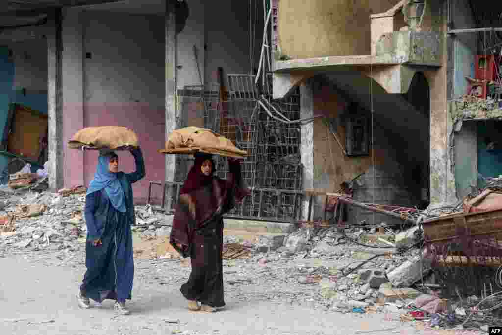 Women carry bread loaves on their heads as they walk past a building damaged by Israeli bombardment in Rafah in the southern Gaza Strip, Feb. 25, 2024