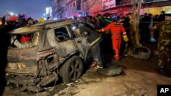 Pripadnici civilne zaštite okupljaju se oko vozila unišenog u napadu drona američke vojske, u istočnom Bagdadu, Iraj, 7. februara 2024.