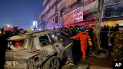 Civil defense members gather at the site of a burned vehicle targeted by a U.S. drone strike in east Baghdad, Iraq, Feb. 7, 2024. 