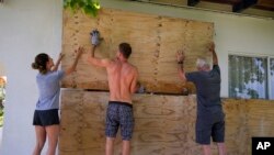 Residents cover the windows of their home in preparation for the arrival of Hurricane Beryl in Bridgetown, Barbados, June 30, 2024. 