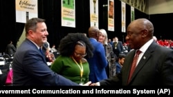 FILE - South African President Cyril Ramaphosa, right, greets opposition Democratic Alliance (DA) leader, John Steenhuisen, left, at the first sitting of Parliament since elections, in Cape Town, June 14, 2024. 