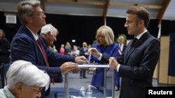 French President Emmanuel Macron casts his ballot flanked by French first lady Brigitte Macron at a polling station to vote in the second round of French parliamentary elections in Le Touquet-Paris-Plage, July 7, 2024. 