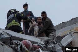 Emergency workers and volunteers rescue a child at a site of an apartment building damaged by a Russian military strike, in Sloviansk, Donetsk region, Ukraine, April 14, 2023.