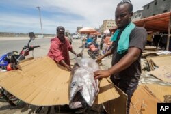 Seorang pria Somalia di sebuah pasar di Mogadishu, Somalia, menyiapkan ikan untuk berbuka di bulan suci Ramadan, Kamis, 23 Maret 2023. (AP/Farah Abdi Warsameh)