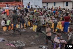 FILE - Congolese army soldiers walk among the displaced Congolese women and children at the Bulengo camp a few kilometers from the center of Goma, eastern Democratic Republic of Congo, on Feb. 16, 2024.