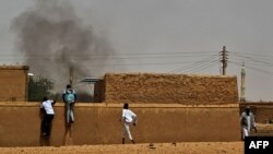 People flee as smoke billows on the first day of the Eid al-Adha Muslim holiday in Wad Hamid, about 100 kilometers north of Sudan's capital, June 28, 2023. 