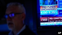 A TV displays news about the Federal Reserve as traders work on the floor at the New York Stock Exchange in New York, June 14, 2023. 