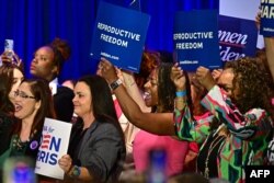 Women hold signs as they listen to Vice President Kamala Harris speak on reproductive freedom at El Rio Neighborhood Center in Tucson, Ariz., April 12, 2024.
