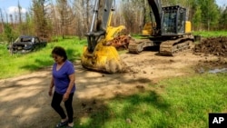 FILE - Carrol Johnston, who lost her home in a May wildfire, walks through her property in the East Prairie Metis Settlement, Alberta, July 4, 2023.