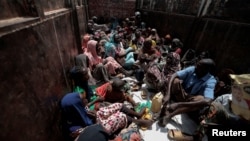 Sudanese people who fled the conflict in Geneina in Sudan's Darfur region, sit on a truck that will relocate them from a school where they were temporarily accommodated to a refugee camp in Adre, Chad, July 23, 2023.