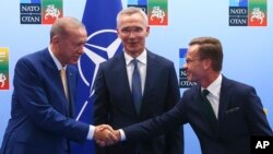 Turkey's President Recep Tayyip Erdogan, left, shakes hands with Sweden's Prime Minister Ulf Kristersson, right, as NATO Secretary General Jens Stoltenberg looks on prior to a meeting ahead of a NATO summit in Vilnius, Lithuania, July 10, 2023.