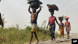FILE - Women and children return from their farmlands after the day's work in Agatu village in Nigeria, Jan 5, 2022. The U.N. warns that the lean season in the country will heighten food security and nutrition crises there.