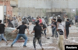 Para pengunjuk rasa bentrok dengan anggota polisi ketika mereka berkumpul di dekat kedutaan Swedia di Baghdad beberapa jam setelah kedutaan itu diserbu dan dibakar menjelang pembakaran Al-Qur'an yang diperkirakan terjadi di Stockholm, di Baghdad, Irak, 20 Juli 2023. (Foto: REUTERS/Ahmed Saad)