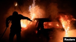 FILE - A French firefighter works to extinguish a burning car during the fifth day of protests following the death of Nahel, a 17-year-old teenager killed by a French police officer in Nanterre during a traffic stop, in Tourcoing, France, July 2, 2023.