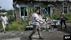 A member of a volunteer medics team walks past a destroyed building in the village of Staryi Karavan, Donetsk region, on July 21, 2023, amid the Russian invasion of Ukraine. 
