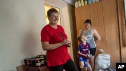 Nataliia Skakun, former resident of Oleshky, Ukraine, stands next to her daughter Anastasia and grandson Maxim at their apartments in Mykolaiv, Ukraine, Tuesday, July 4, 2023.