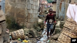 FILE - A boy walks past sewage around houses in Abuja, Nigeria, Sept. 3, 2021. Nigerian authorities have declared a national emergency and activated response operations to control the spread of a cholera outbreak that has killed more than 50 people. 