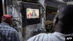 Watu wakimtazama rais Macky Sall wakati wa mkutano na waandishi wa habari uliotangazwa moja kwa moja na televisheni ya taifa . Picha na Michele Cattani / AFP