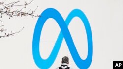 Seorang pria beridiri di depan logo Meta yang terpasang di luar markas perusahaan tersebut di Menlo Park, California, pada 7 Maret 2023. (Foto: AP/Jeff Chiu)