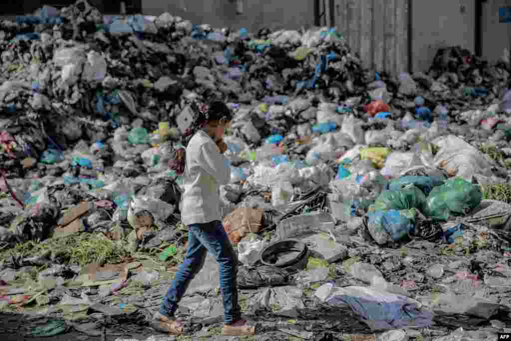A Palestinian girl walks along a garbage-filled street in Gaza City, Feb. 24, 2024.