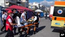 Petugas paramedis membawa seorang migran, yang selamat dari insiden tenggelamnya kapal migran, ke dalam ambulans di pelabuhan Kalamata, Yunani, pada 14 Juni 2023. (Foto: AP/Thanassis Stavrakis)