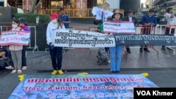 កូដករណាហ្គាវើលដ៍ឈរលើកបដាតវ៉ានៅពីមុខក្រុមហ៊ុនណាហ្គាវើលដ៍ ក្នុងរាជធានីភ្នំពេញ កាលពីថ្ងៃទី២៥ ខែកុម្ភៈ ឆ្នំា២០២៤។ (ស៊ឹម ចាន់សំណាង/វីអូអេ)
