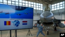 一名罗马尼亚军人走过停放在费泰什蒂外的一处军事基地的机库内的一架荷兰皇家空军的F-16战斗机。(2023年11月13日)