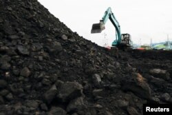 Seorang pekerja mengoperasikan kendaraan berat untuk menurunkan batubara dari tongkang ke truk untuk didistribusikan, di pelabuhan Karya Citra Nusantara di Jakarta Utara, 13 Januari 2022. (REUTERS/Willy Kurniawan)