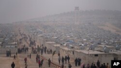 FILE - Syrians walk along in a refugee camp for displaced people run by the Turkish Red Crescent in Sarmada district, north of Idlib city, Syria, on Nov. 26, 2021.