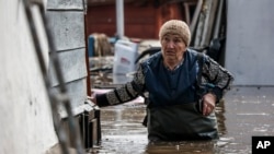 A woman walks near her house in a flooded area in Orenburg, Russia, Wednesday, April 10, 2024. (AP Photo)