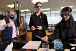 FILE - Valerie Mosser, senior associate faculty, helps students Siari Rodriguez, center, and Crystal Baker, right, during Chemistry 121 class at Everett Community College, March 10, 2023.