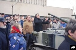 FILE - Lithuanians stand in front of a Red Army armored vehicle as soldiers arrive to take over the main printing house in the center of Vilnius, Jan. 11, 1991.