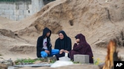 Palestinians visit the graves of their relatives who were killed in the war between Israel and the Hamas militant group on the first day of the Muslim holiday of Eid al-Fitr, in Deir al-Balah, Gaza, Apr. 10, 2024.