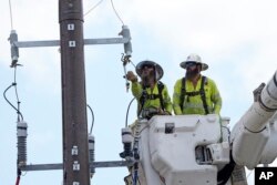 Workers repair a power line on Thursday, June 29, 2023, in Houston. An unrelenting heat wave in Texas is testing the state's power grid as demand soars during a second week of triple-digit temperatures.