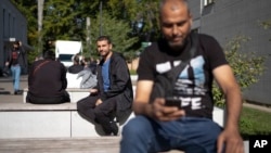 Abdullah al-Shweiti, center, from Homs, Syria, poses for a photo prior to an interview with The Associated Press at the central registration for asylum seekers in Berlin, Germany, Sept. 25, 2023.