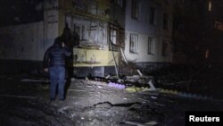 បុរសម្នាក់​ឈរ​ក្បែរ​សំណង់​អគារ​ដែល​ត្រូវបាន​បំផ្លាញ​ដោយសារ​ការ​វាយប្រហារ​តាម​ដ្រូន​របស់​រុស្ស៊ី នៅ​តំបន់ Kharkiv ប្រទេស​អ៊ុយក្រែន កាលពីថ្ងៃទី៣១ ខែមករា ឆ្នាំ២០២៤។ 