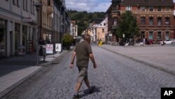 A man cross the main shopping street at the market place of the small city Sonneberg in German federal state Thuringia, July 5, 2023.
