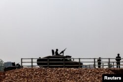 Military personnel stand guard as a stream of people queued at a border crossing to flee Myanmar, after the strategically-vital town of Myawaddy adjoining Thailand fell to anti-junta resistance, in Mae Sot, Tak province, Thailand, April 12, 2024.