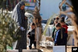 ชาวปาเลสไตน์ไปเยี่ยมสุสานของผู้ที่ถูกสังหารในการทิ้งระเบิดของอิสราเอล และถูกฝังอยู่ภายในพื้นที่โรงพยาบาลชิฟา ของฉนวนกาซ่า เมื่อ 31 ธ.ค. 2566