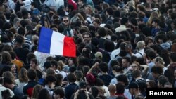 A demonstrator holds a French flag as people gather at the Place de la Republique after partial results in the second round of the early French parliamentary elections, in Paris, July 7, 2024.