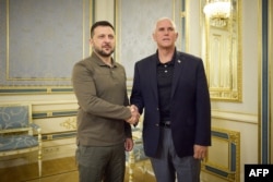 Ukrainian President Zelensky (L) and former US Vice President Mike Pence shake hands prior to their meeting. (Photo by Handout / AFP)