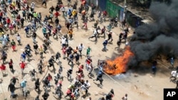 Protesters run toward riot police officers during a mass rally called by the opposition leader Raila Odinga over the high cost of living in Kibera Slums, Nairobi, March 27, 2023.